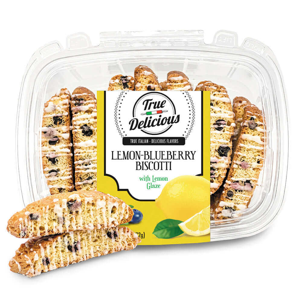 A clear plastic container of True Delicious Lemon Blueberry Biscotti with Glaze displays several biscotti inside and two in front. The label shows images of fresh lemon and blueberry.