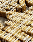 Biscotti cookies with white icing drizzled over them on a white surface