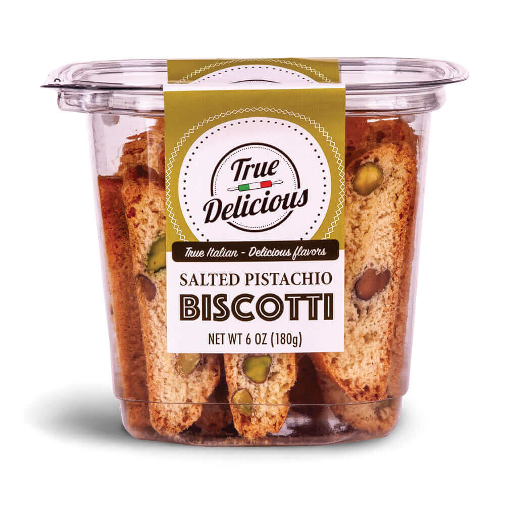 A clear plastic container labeled True Delicious Salted Pistachio Biscotti displays handcrafted cookies with pistachio pieces inside and contains 6 oz (180g) of Italian biscotti.
