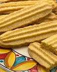 A decorative plate displays True Delicious Cookies Collection (10-Pack) Italian cookies, golden and ridged, with one broken to reveal its crumbly inside.