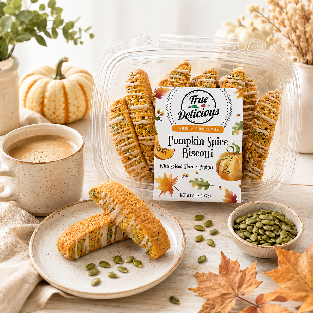 A package of True Delicious Pumpkin Spice Biscotti with Glaze &amp; Pepitas is served alongside a cup of coffee, a small bowl of pepitas, autumn leaves, and a decorative pumpkin atop a wooden table, creating a cozy fall ambiance. Made with natural ingredients, these biscotti capture the essence of the season.