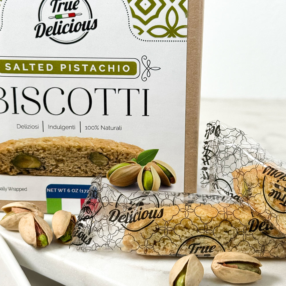 True Delicious Elegant Box Salted Pistachio Biscotti, individually wrapped for freshness—authentic Italian biscotti with cracked pistachio nuts in decorative clear packaging on a white surface.